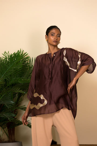 Brown silk shirt for women with handcrafted patch detailing, contemporary Indian luxury wear styled with neutral trousers.
