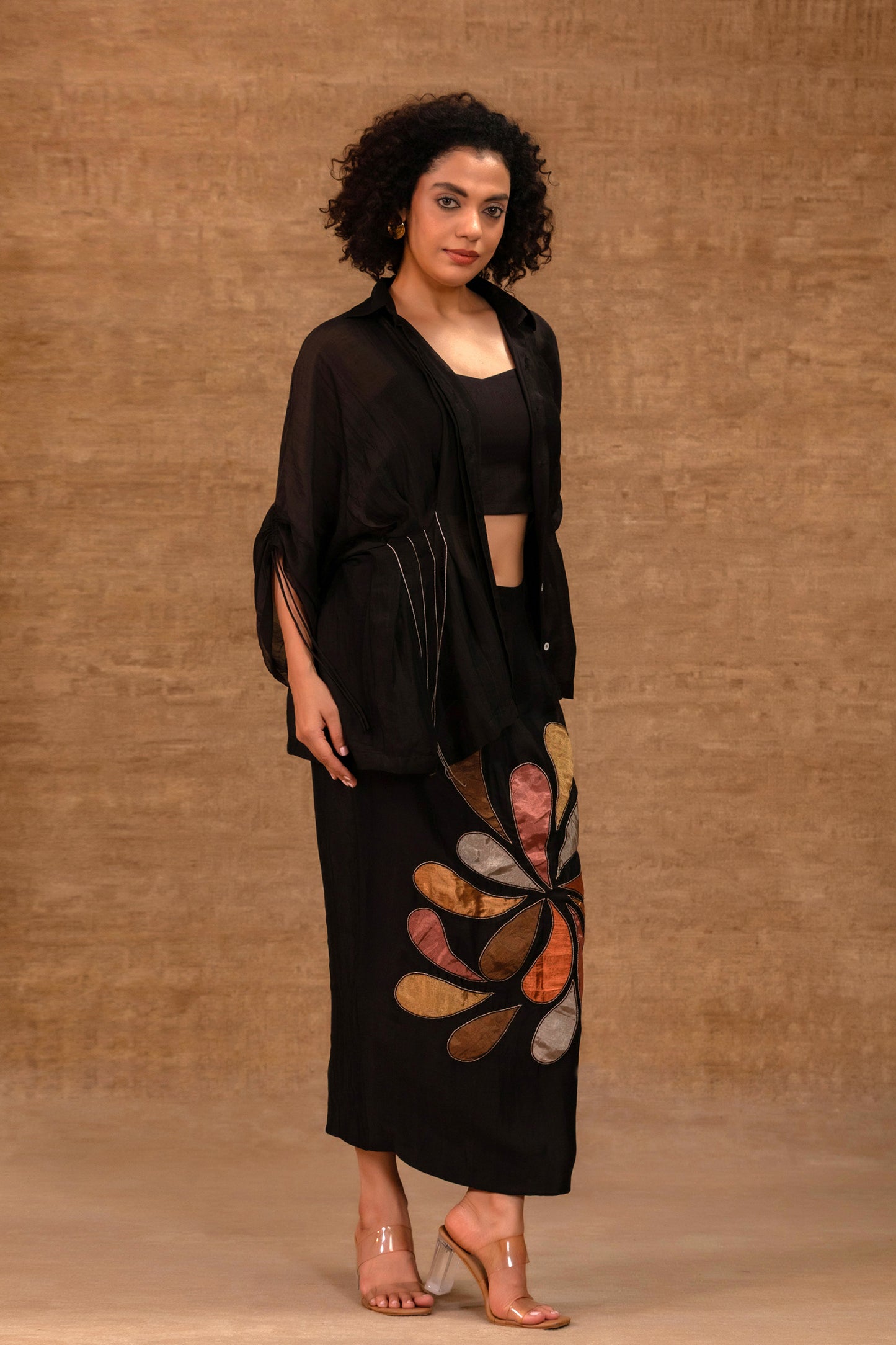 Model in a black silk chanderi pleated shirt with a patch skirt and bustier — Eeda