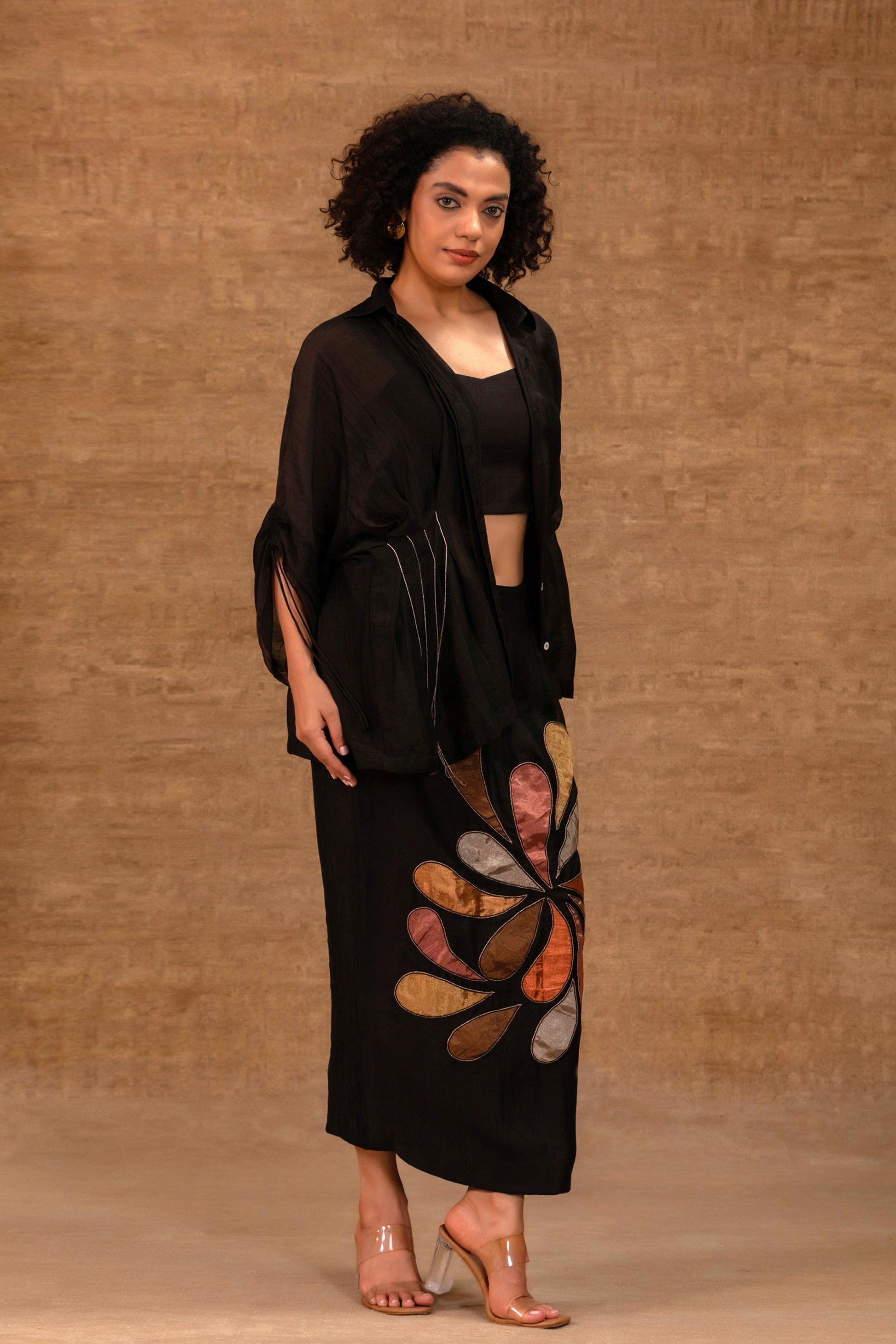 Model in a black silk chanderi pleated shirt with a patch skirt and bustier — Eeda