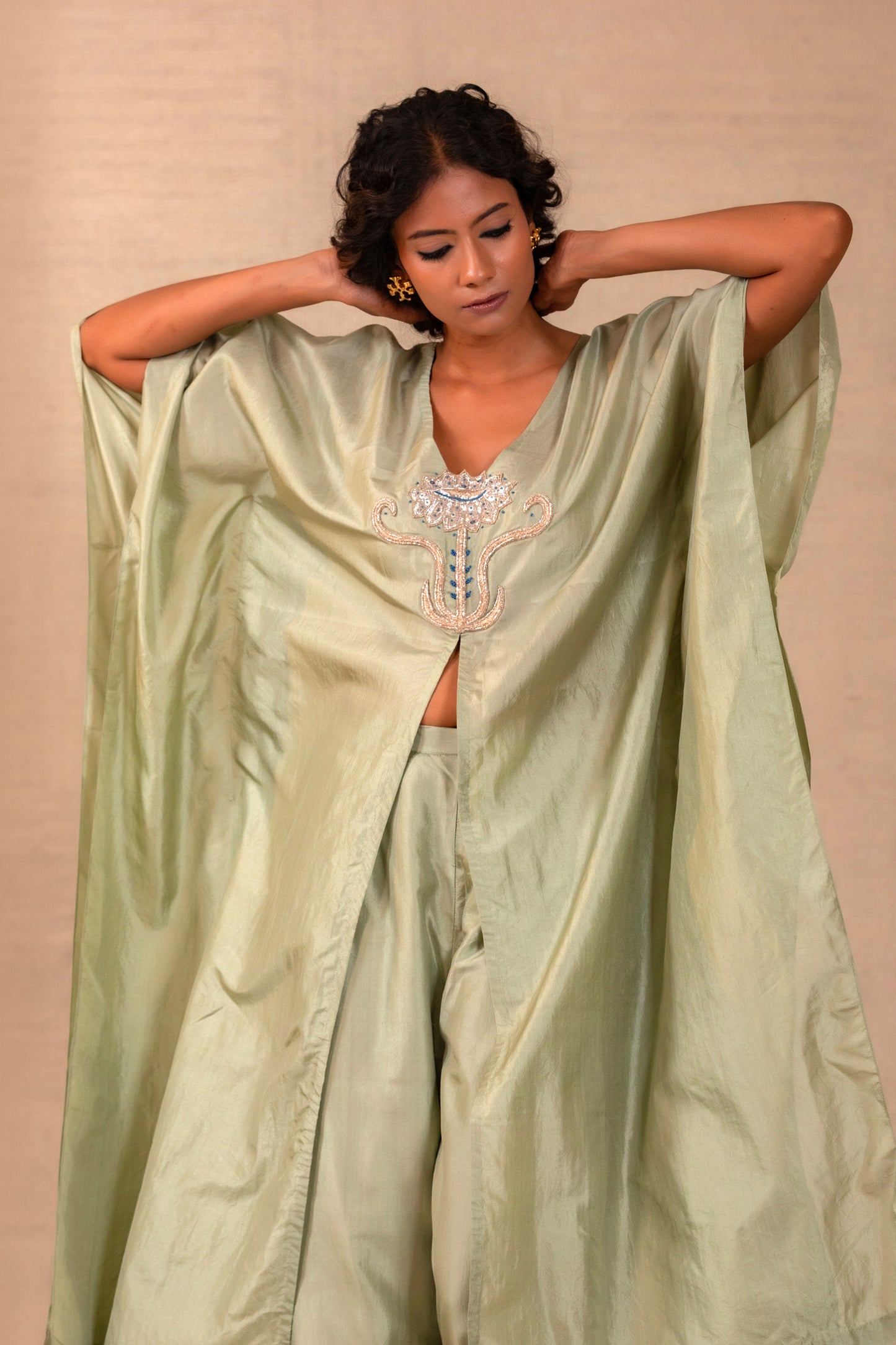 Woman in a sage silk kurta set with a flower motif at the neck and straight pants — Eeda Silsila