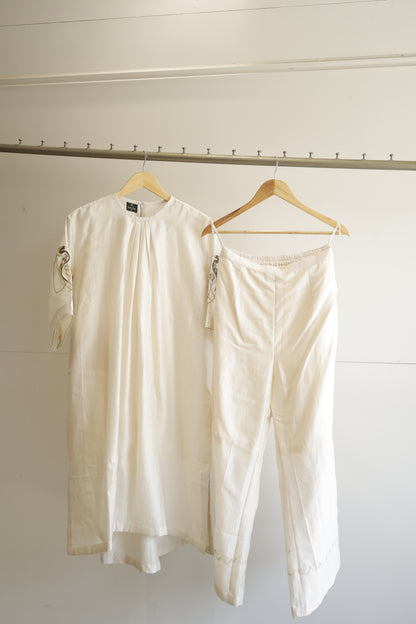 eeda Tinka — chanderi gathered kurta with hand-embroidered sleeve and chain detail, paired with white straight trousers, handcrafted in Varanasi
